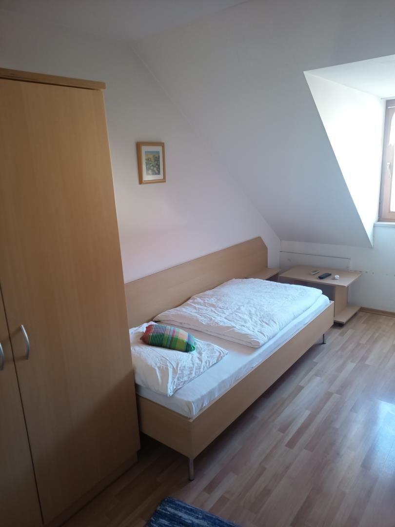 Schlafzimmer mit Dachschräge, Bett, Kleiderschrank und Nachttisch.