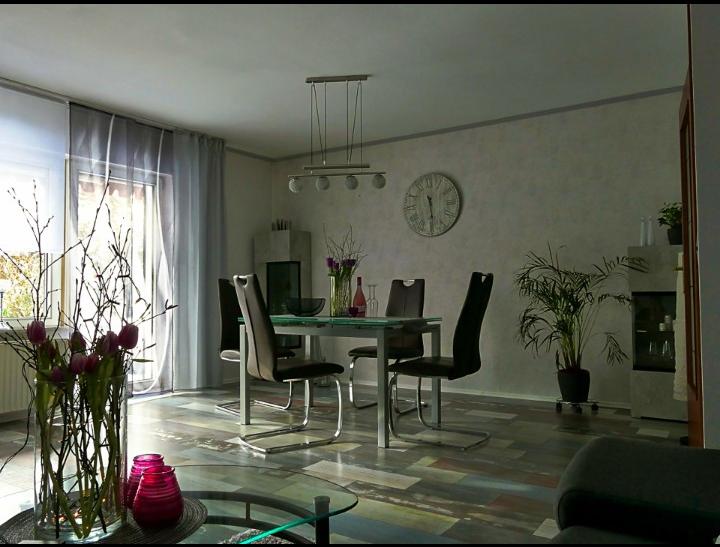 Esszimmer mit Glas-Tisch, schwarzen Stühlen und Pflanzen.