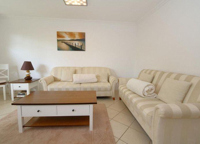 Wohnzimmer mit zwei Sofas, Tisch und Wandbild.