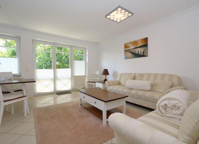 Wohnzimmer mit Sofa, Couchtisch und Fenstern zum Garten.