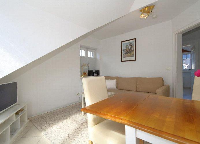 Wohnbereich mit Sofa, Esstisch und Fernseher unter Dachschrägen.