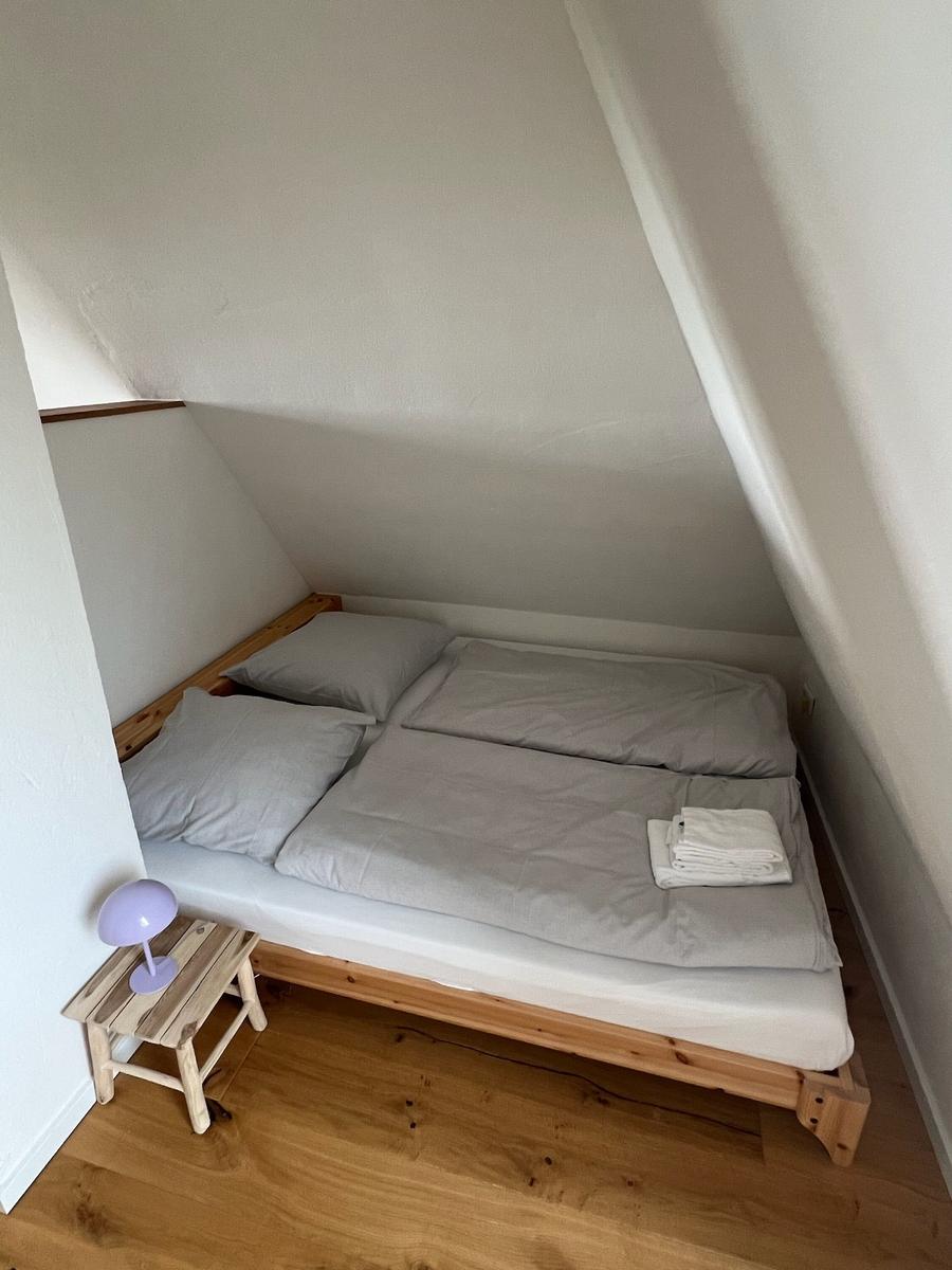 Schlafzimmer mit Doppelbett, Holzboden und Stehlampe.