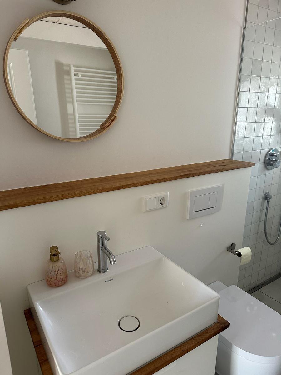 Badezimmer mit Waschbecken, Spiegel und Dusche.