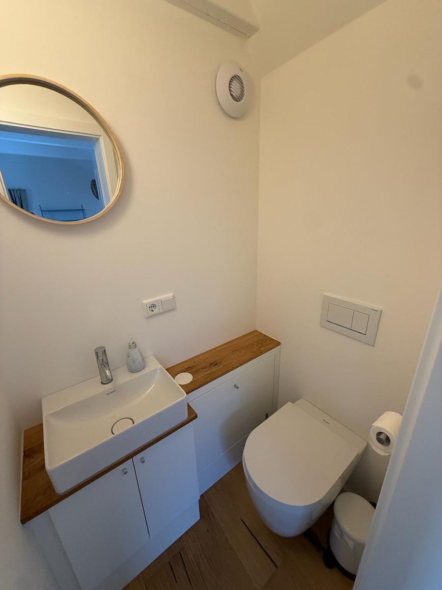 Badezimmer mit Waschbecken, Spiegel und Toilette.