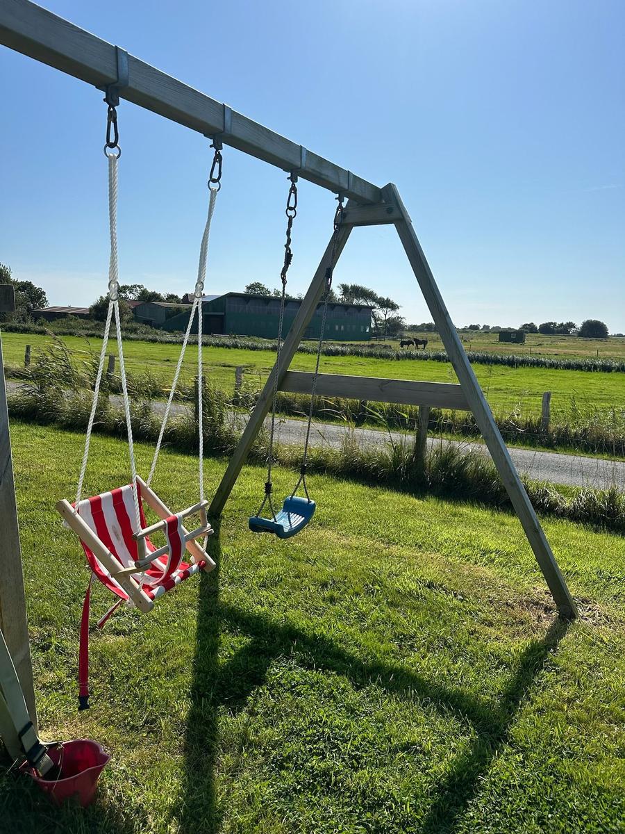 Schaukeln im Garten mit Blick auf Weide und Bauernhof.