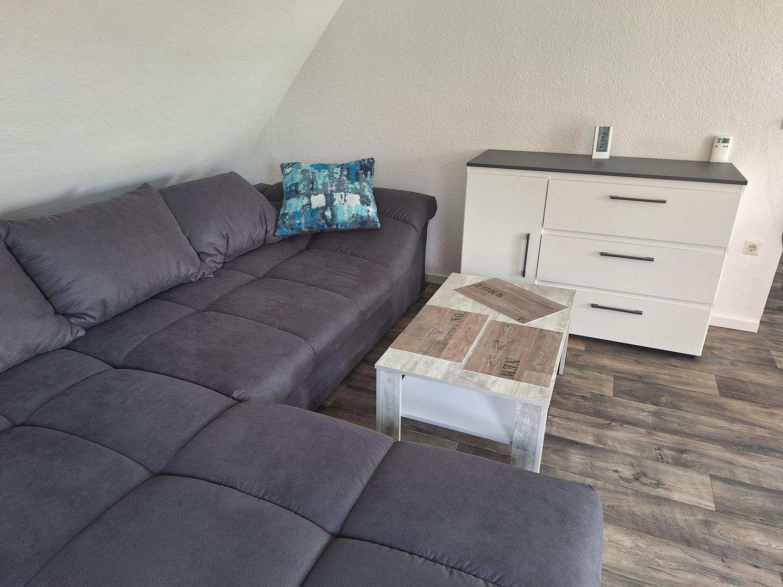 Living room with gray sofa, wooden floor, and white cabinets.