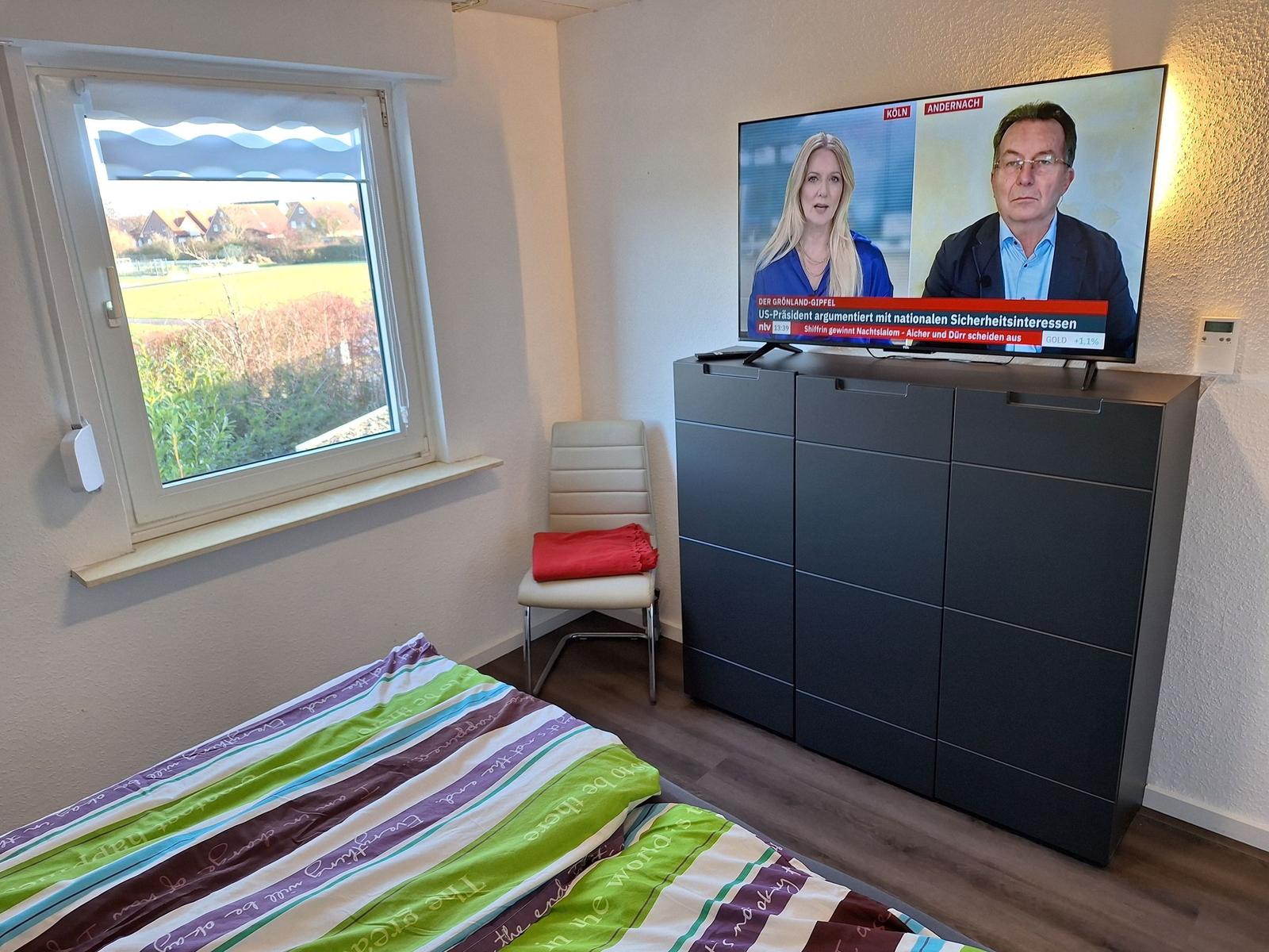 Bedroom with bed, window, and TV on cabinet