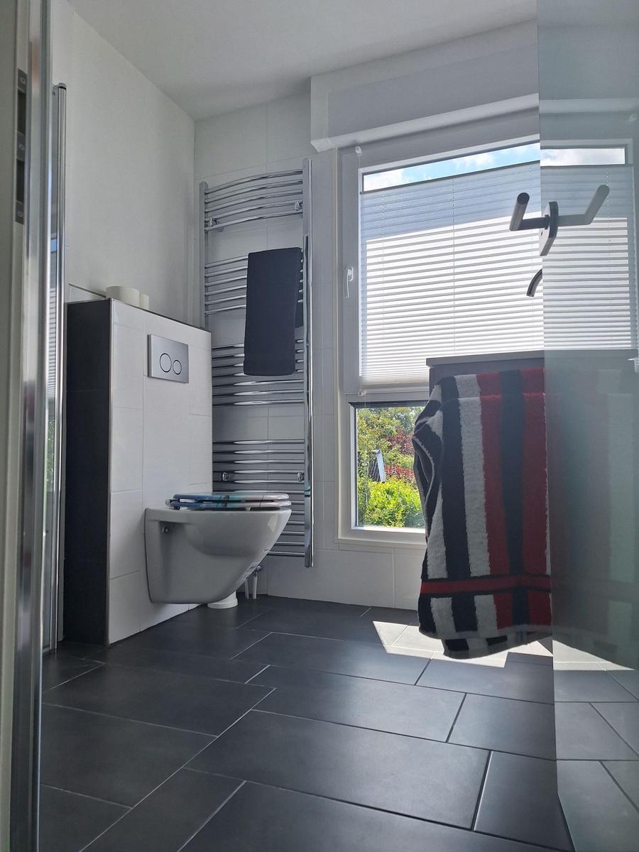 Bathroom with toilet, heater, and window with blinds.
