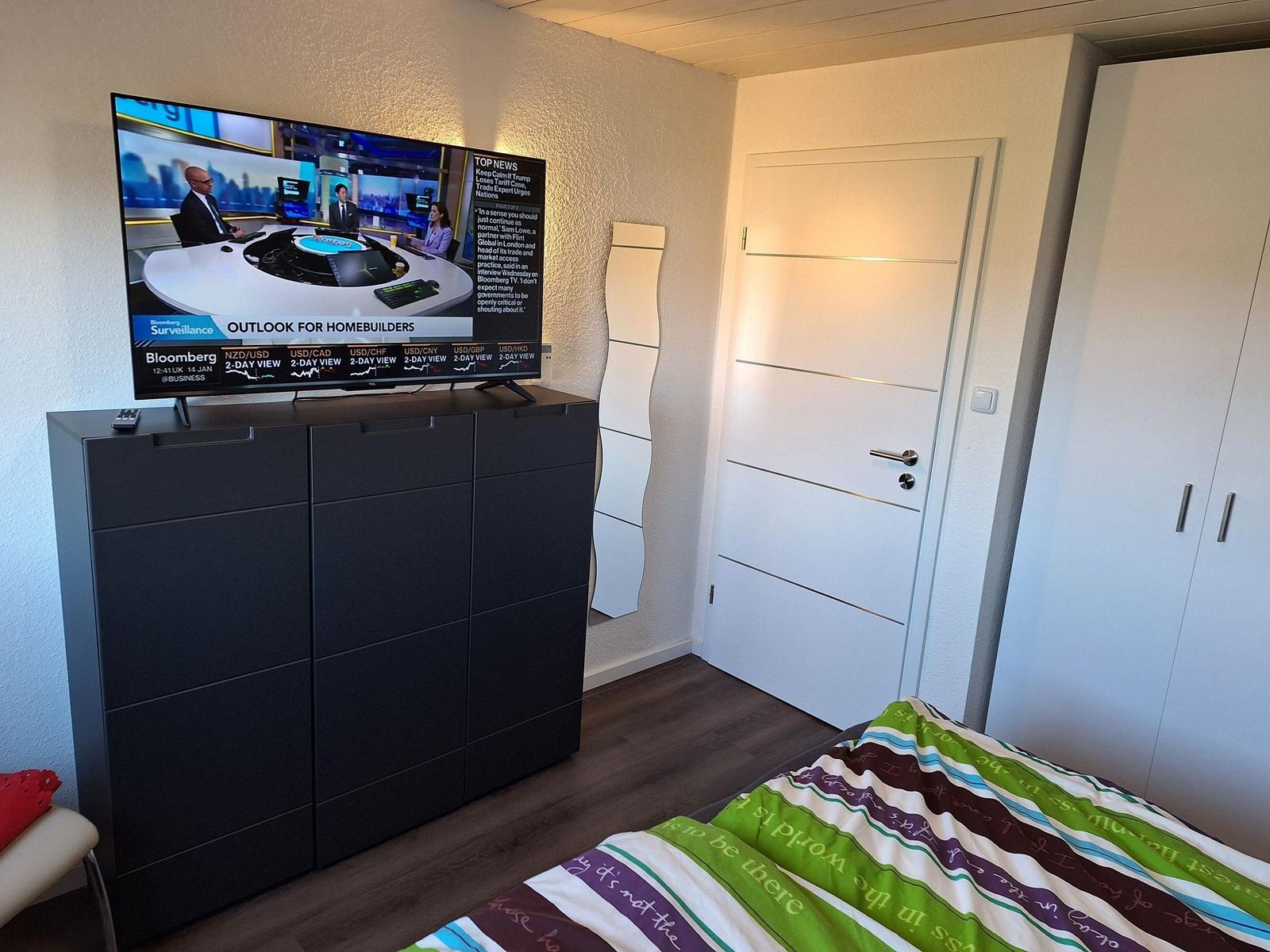 Bedroom with bed, wardrobe, and TV on dresser.