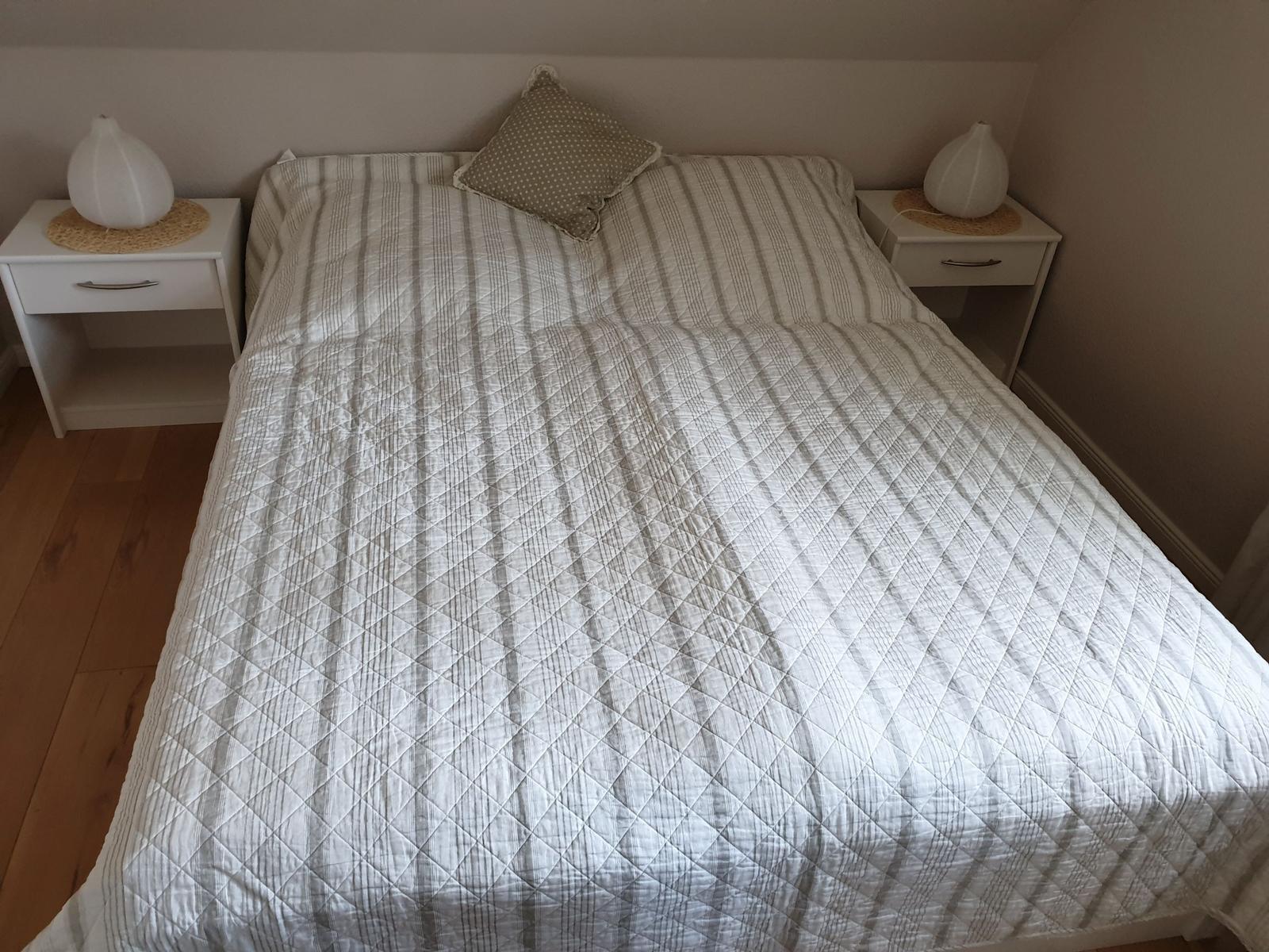 Ein Bett mit gestreifter Bettwäsche und zwei Nachttischen mit Lampen.