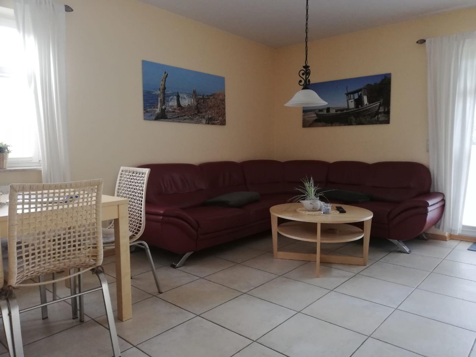 Wohn- und Essbereich mit rotem Sofa, Holztisch und Wandbildern.