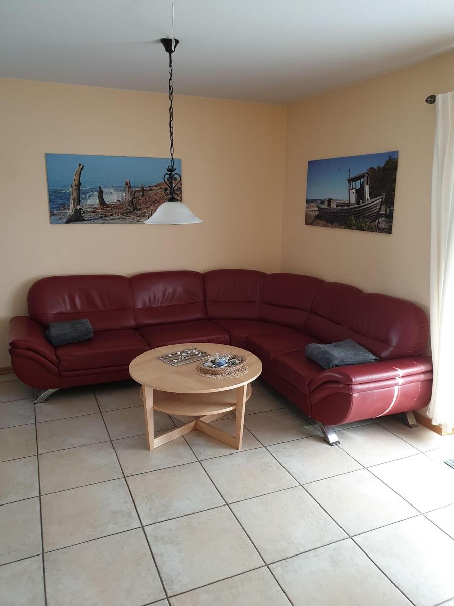 Roter Ledersofa im Wohnzimmer mit runden Tisch und Wandbildern.