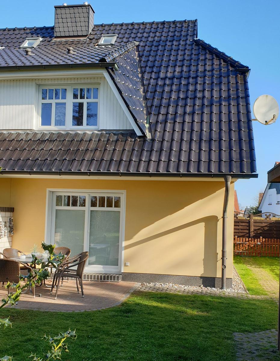 Haus mit Terrasse, Garten und Dachfenstern. Satellitenschüssel an der Wand.