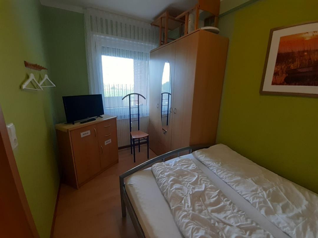 Schlafzimmer mit Bett, Kleiderschrank und Fernseher.