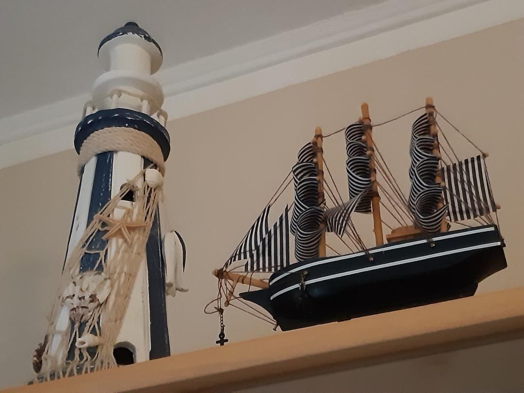 Modell eines Leuchtturms und eines Segelschiffs auf einem Regal.