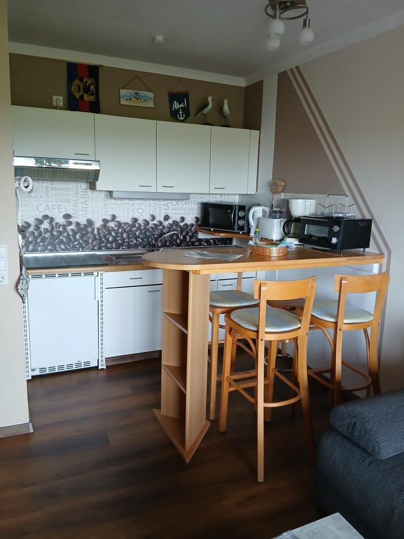 Küche mit Barhocker und Kochgeräten an der Wand