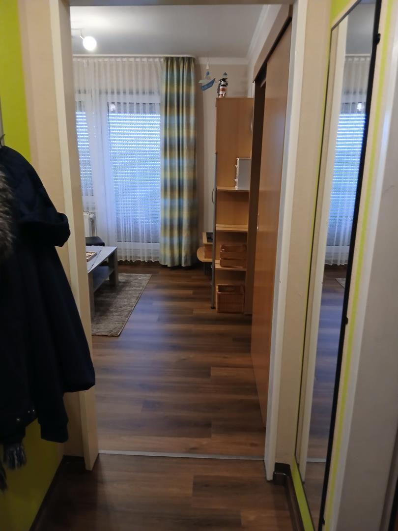 Schlafzimmer mit Holzboden, Gardinen und Schrank