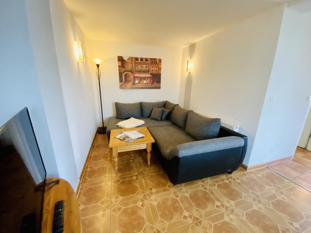 Wohnzimmer mit Ecksofa, Holztisch und Wandbild