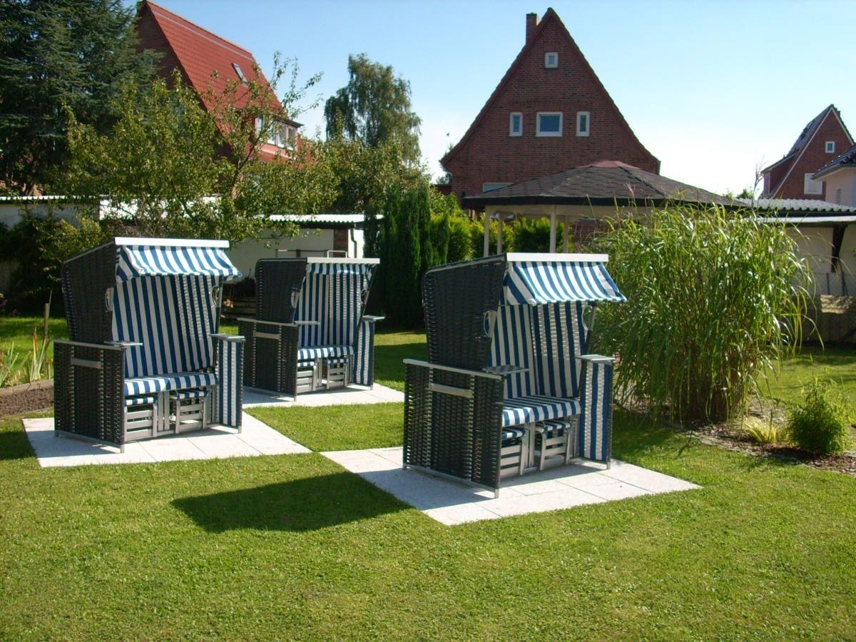Drei Strandkörbe mit blau-weißen Streifen stehen auf einer Terrasse im Garten.