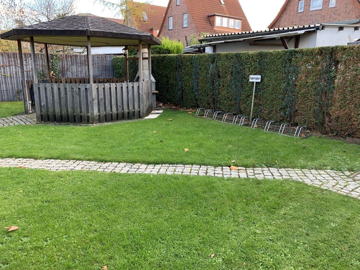 Garten mit Pavillon, Rasenfläche und Fahrradständern an der Hecke.