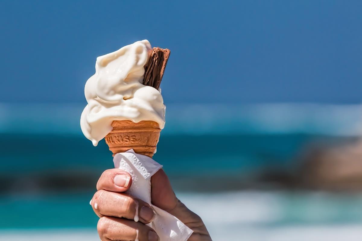 Eine Hand hält ein Eis mit Schokoladenstückchen am Strand.