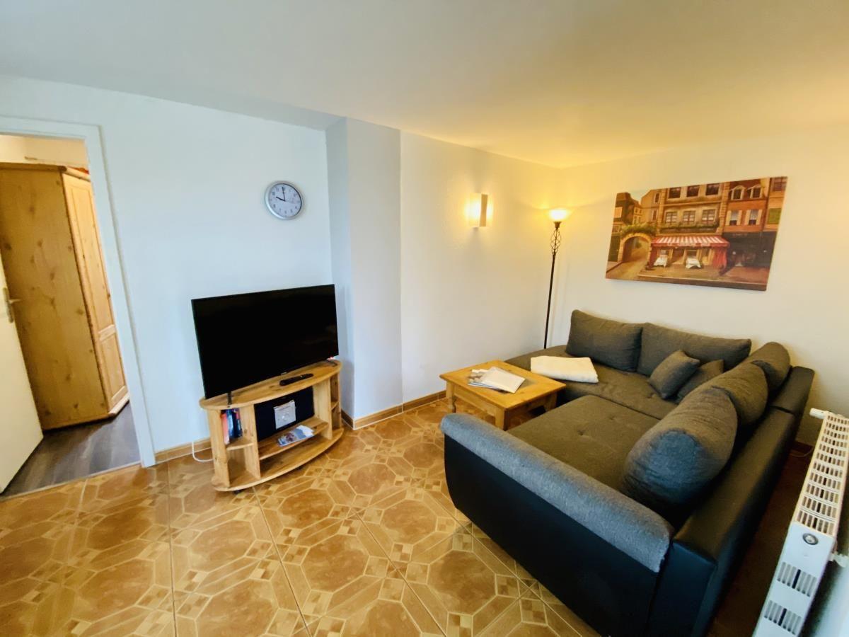 Wohnzimmer mit Sofa, Fernseher und Holzboden