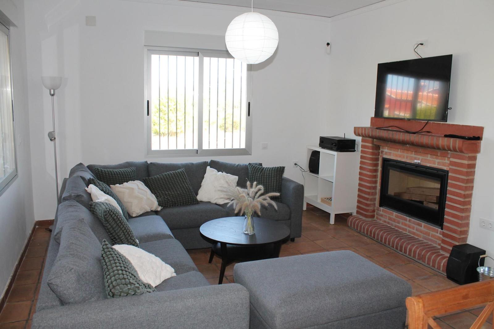 Wohnzimmer mit Sofa, Kamin und Fernseher an der Wand.