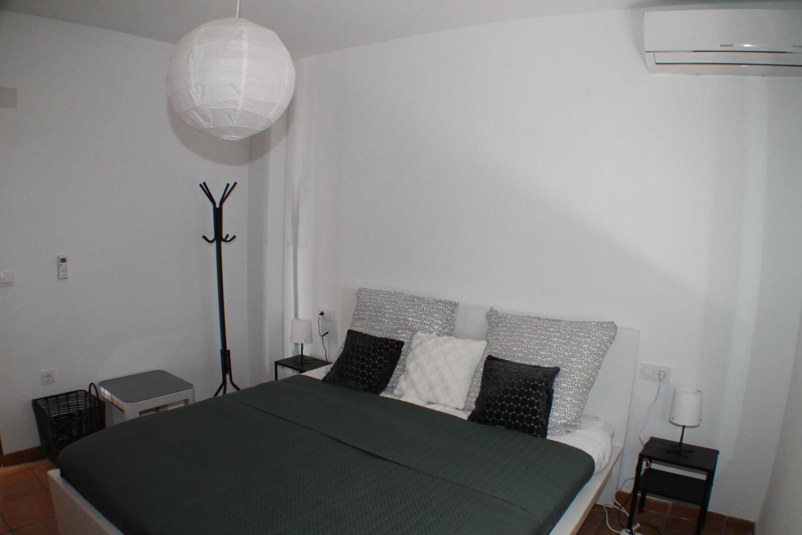 Schlafzimmer mit Bett, Nachttischen und Decke.