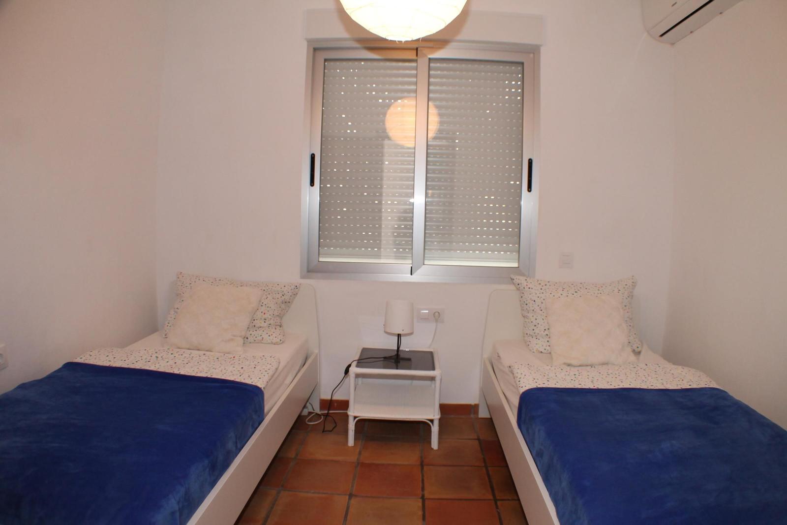 Zwei Einzelbetten mit blauen Decken und einem Nachttisch mit Lampe.