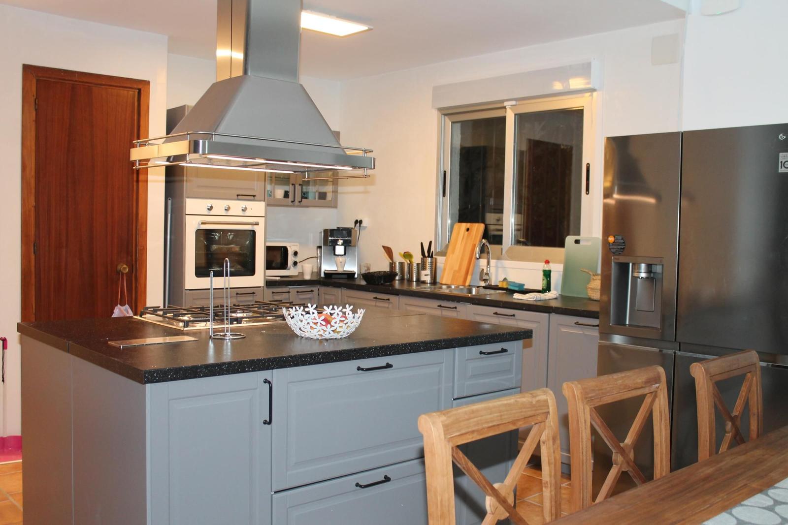 Moderne Küche mit Edelstahlgeräten und Holzstühlen an der Insel.