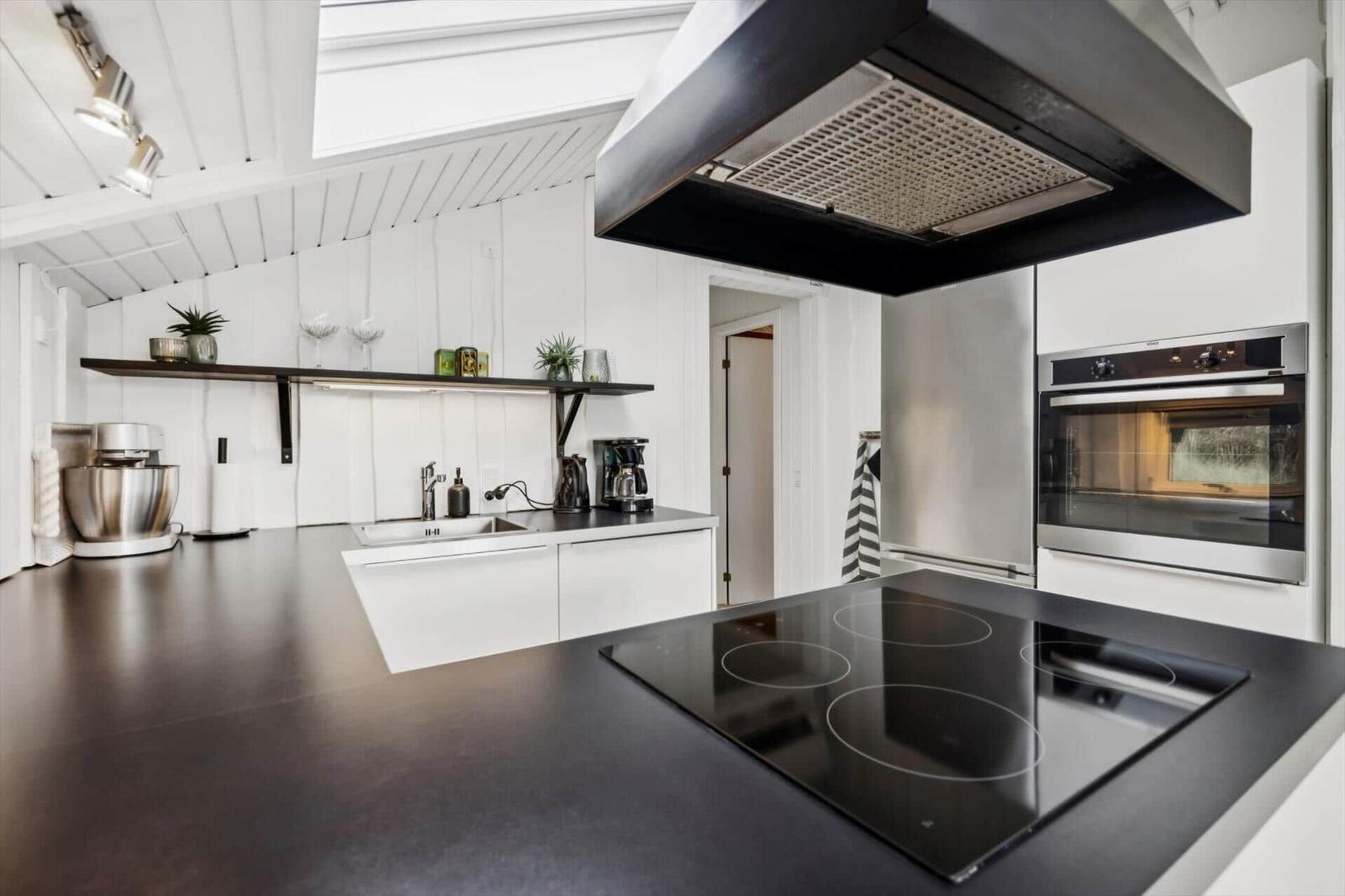 Modern kitchen with black countertop, stainless steel appliances, and white cabinets.