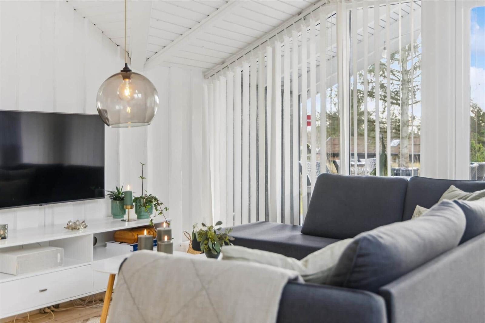 Living room with sofa, TV, and large windows.