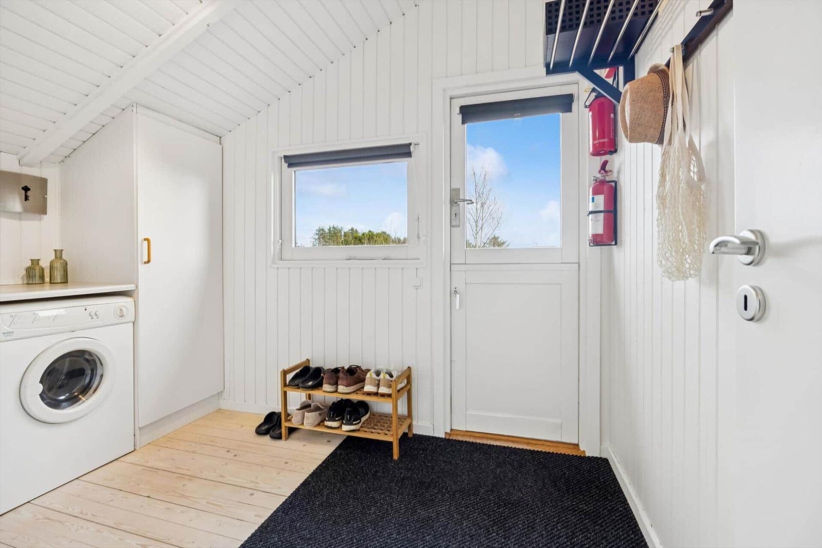 Entrance with washing machine, shoe rack, and door with window.