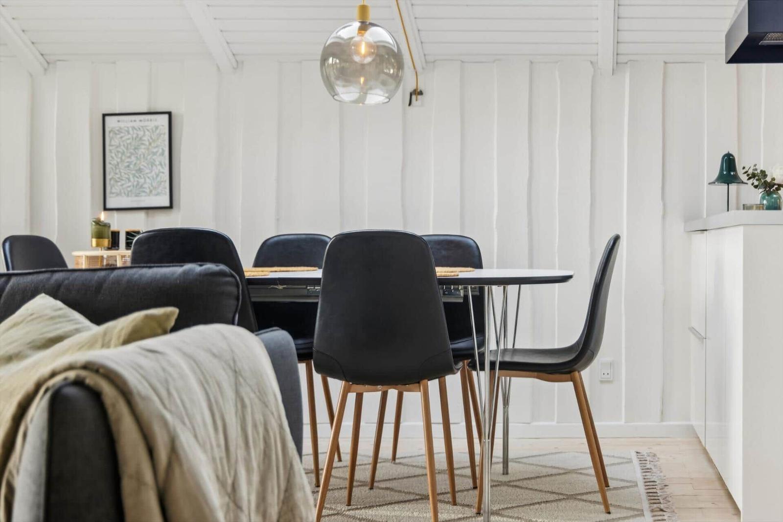 Dining room with table, chairs, and pendant light. White walls and wooden floor.