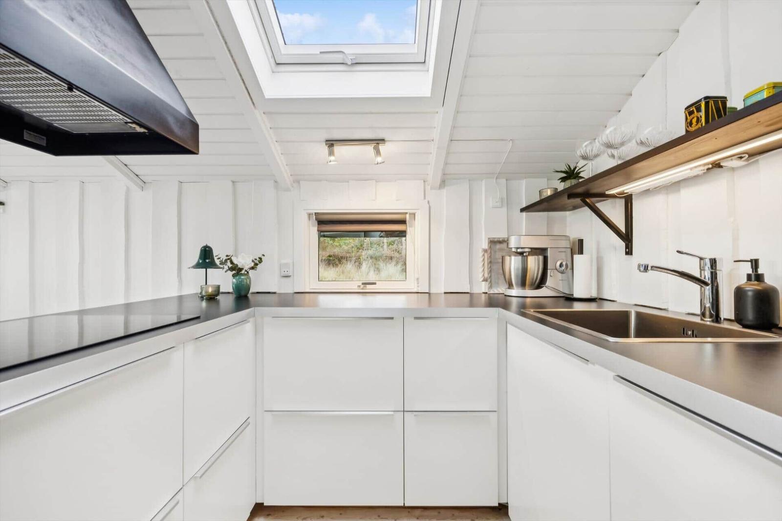 Kitchen with white cabinets, stainless steel sink, and skylight.