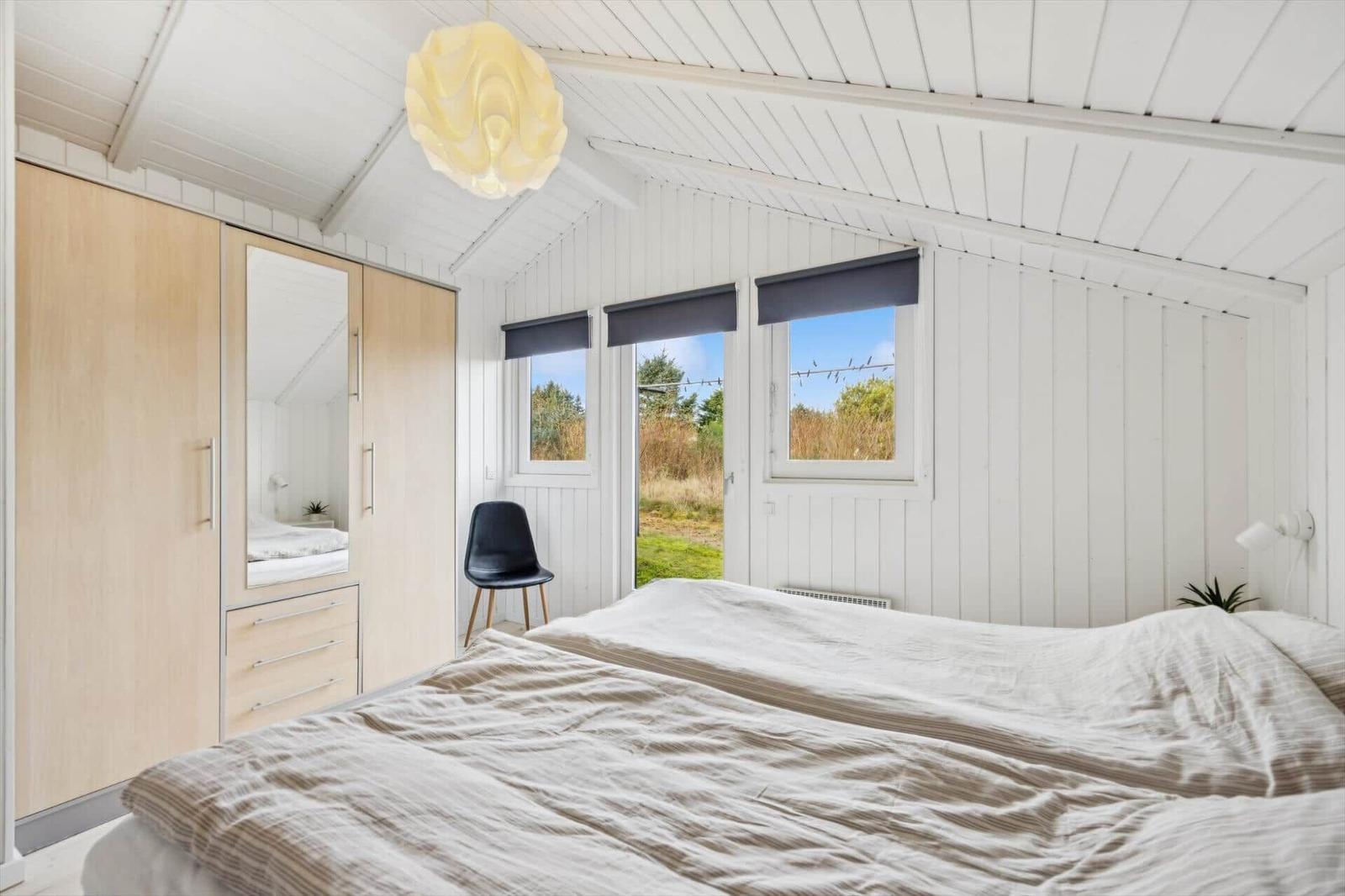 Bedroom with double bed, wardrobe, and windows to the garden.