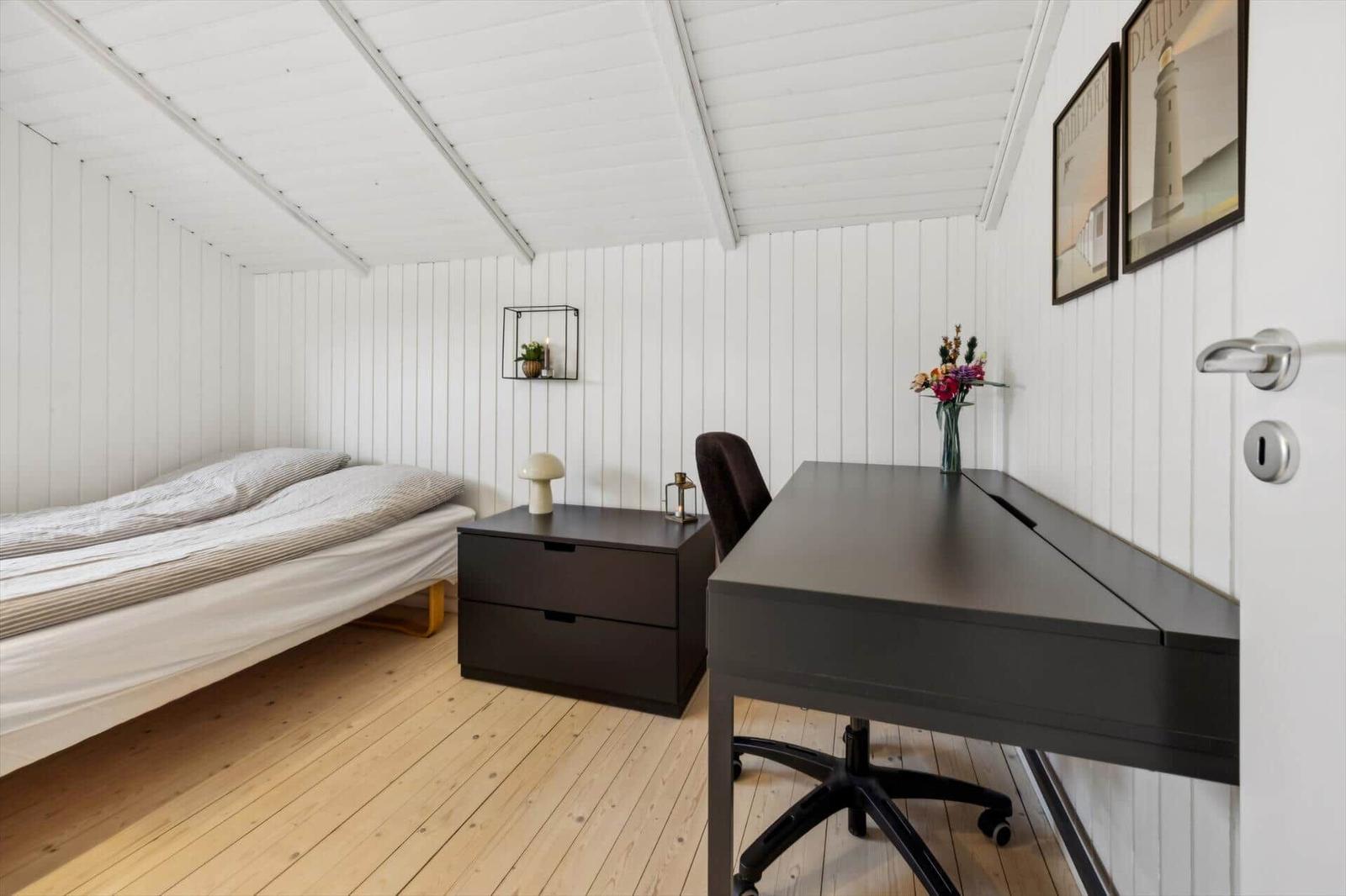 Bedroom with bed, desk, and wall pictures.