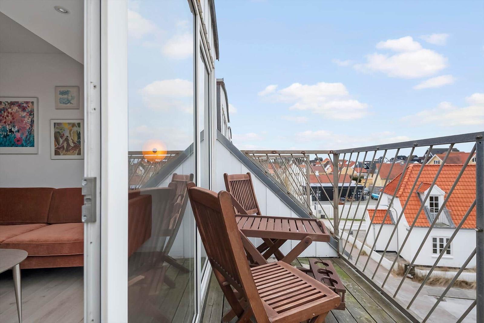 Terrace with wooden chairs and view of red roofs.