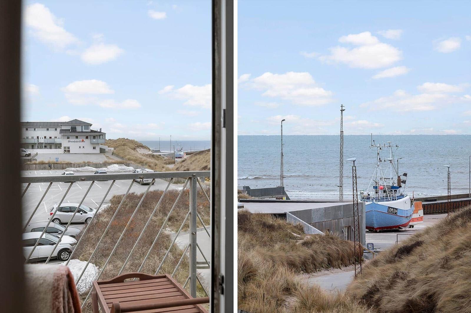 View from balcony over harbor with fishing boat and beach.