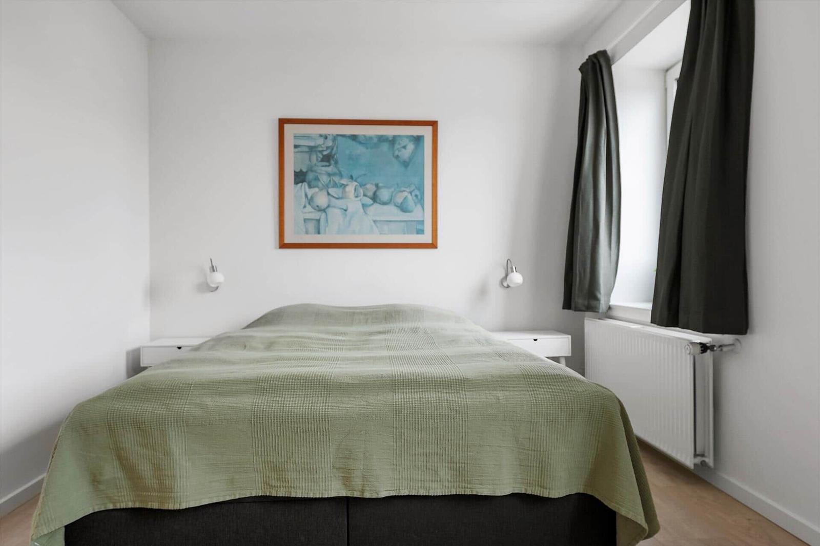 Bedroom with bed, wall art, and window with curtains.