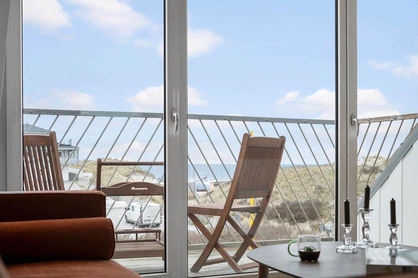 Terrace with sea and dunes view. Wooden chairs and table with candles.
