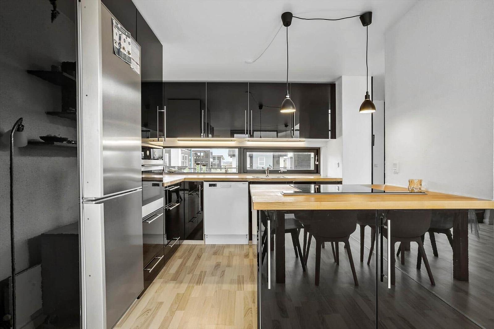 Modern kitchen with dining area, wooden floor, and black cabinets.