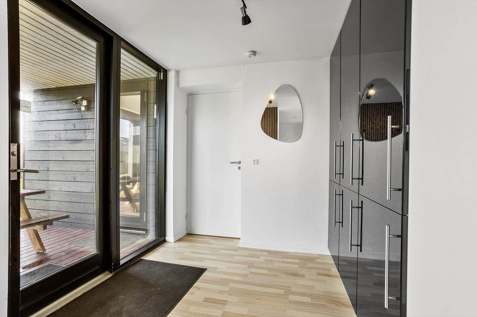 Entrance with glass doors, wooden floor, and modern mirror on the wall.