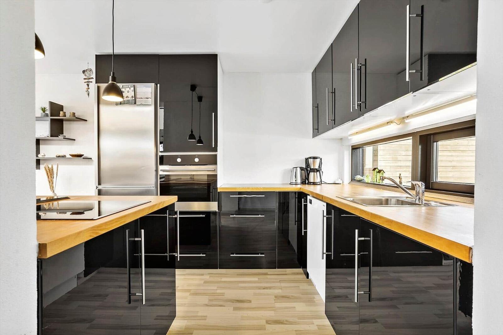 Modern kitchen with dark cabinets, wooden countertops, and stainless steel appliances.