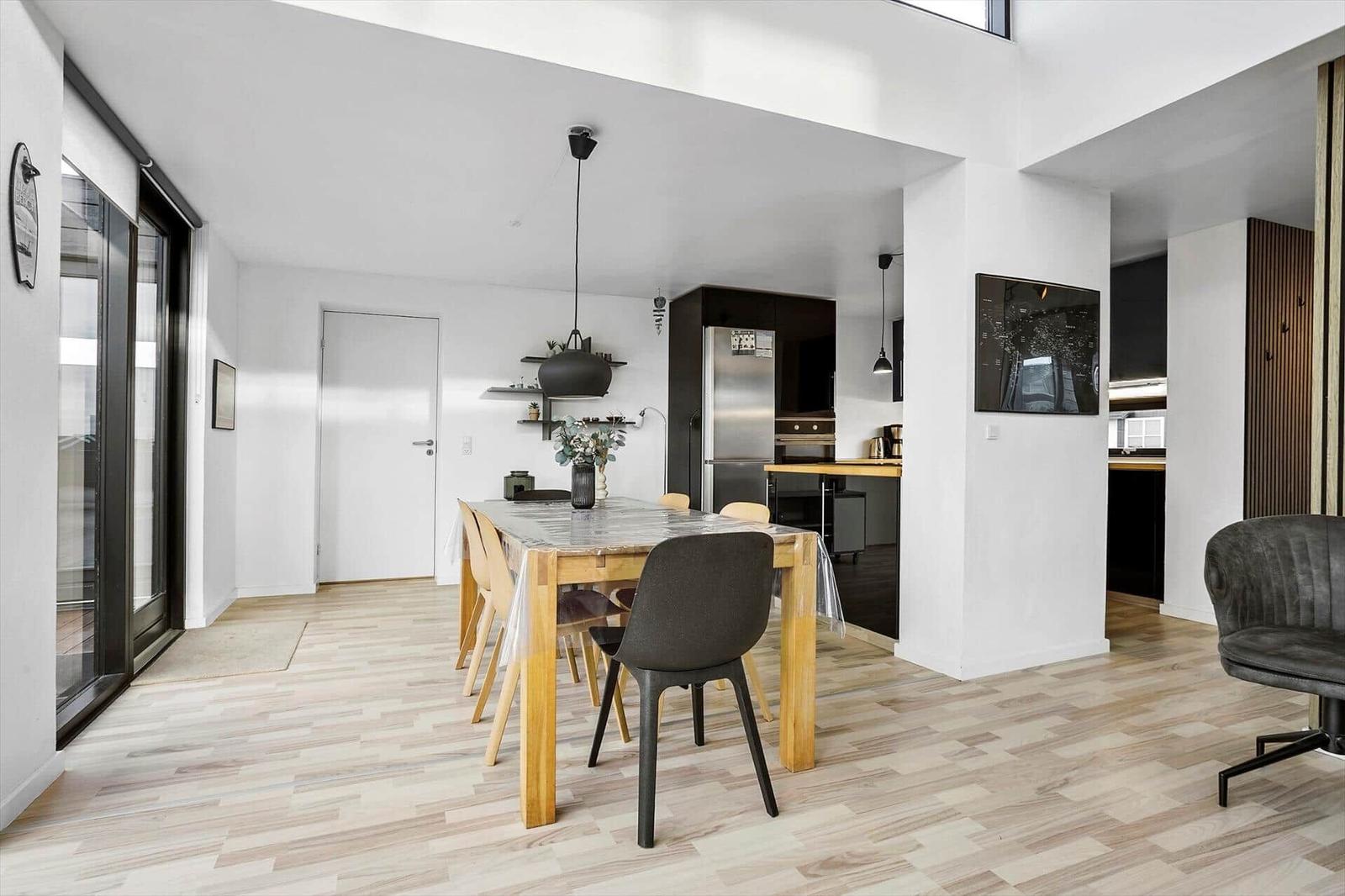 Dining room with table, chairs, and kitchen area in background.
