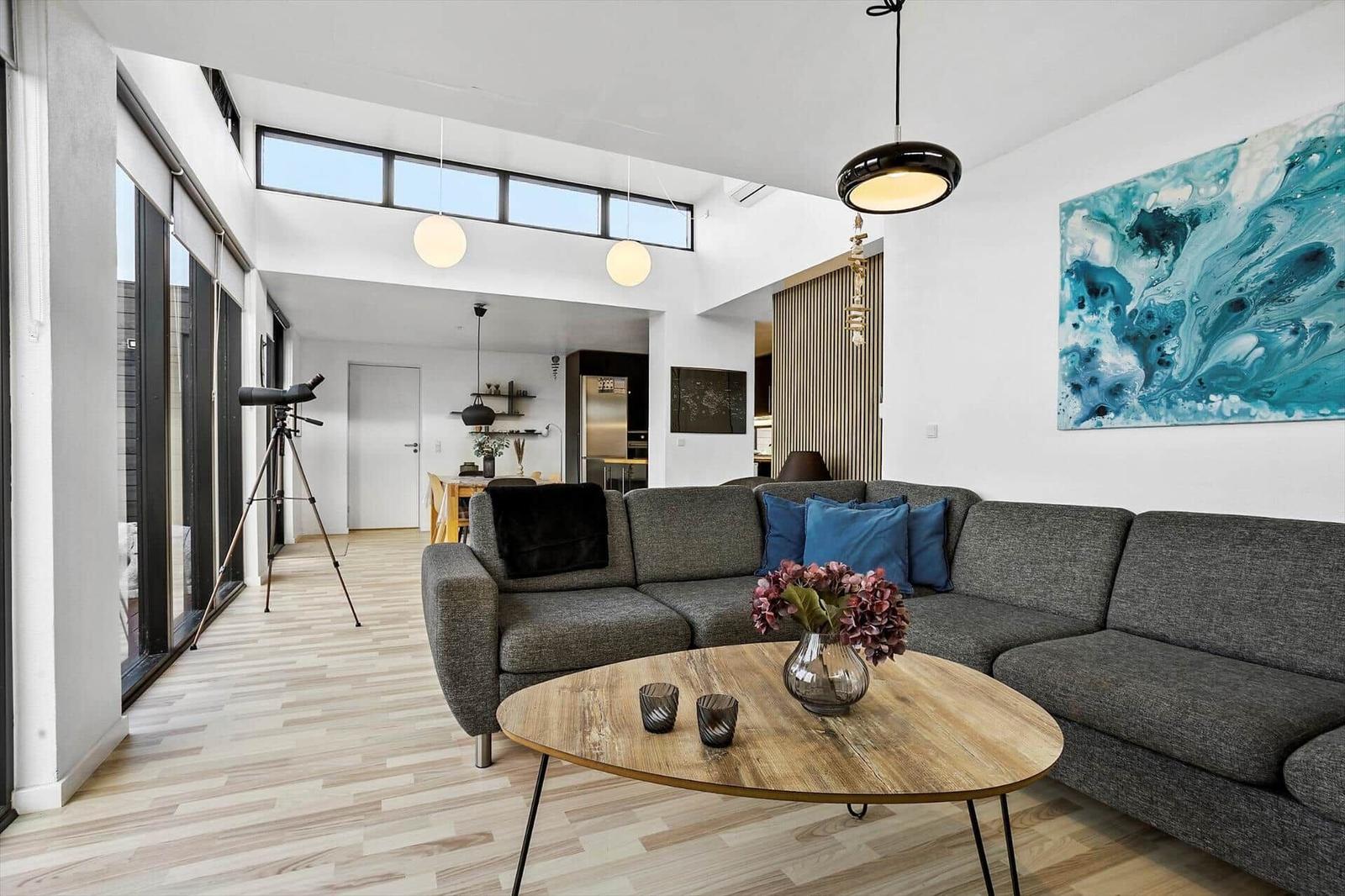 Living room with gray sofa, wooden table, and blue wall art.