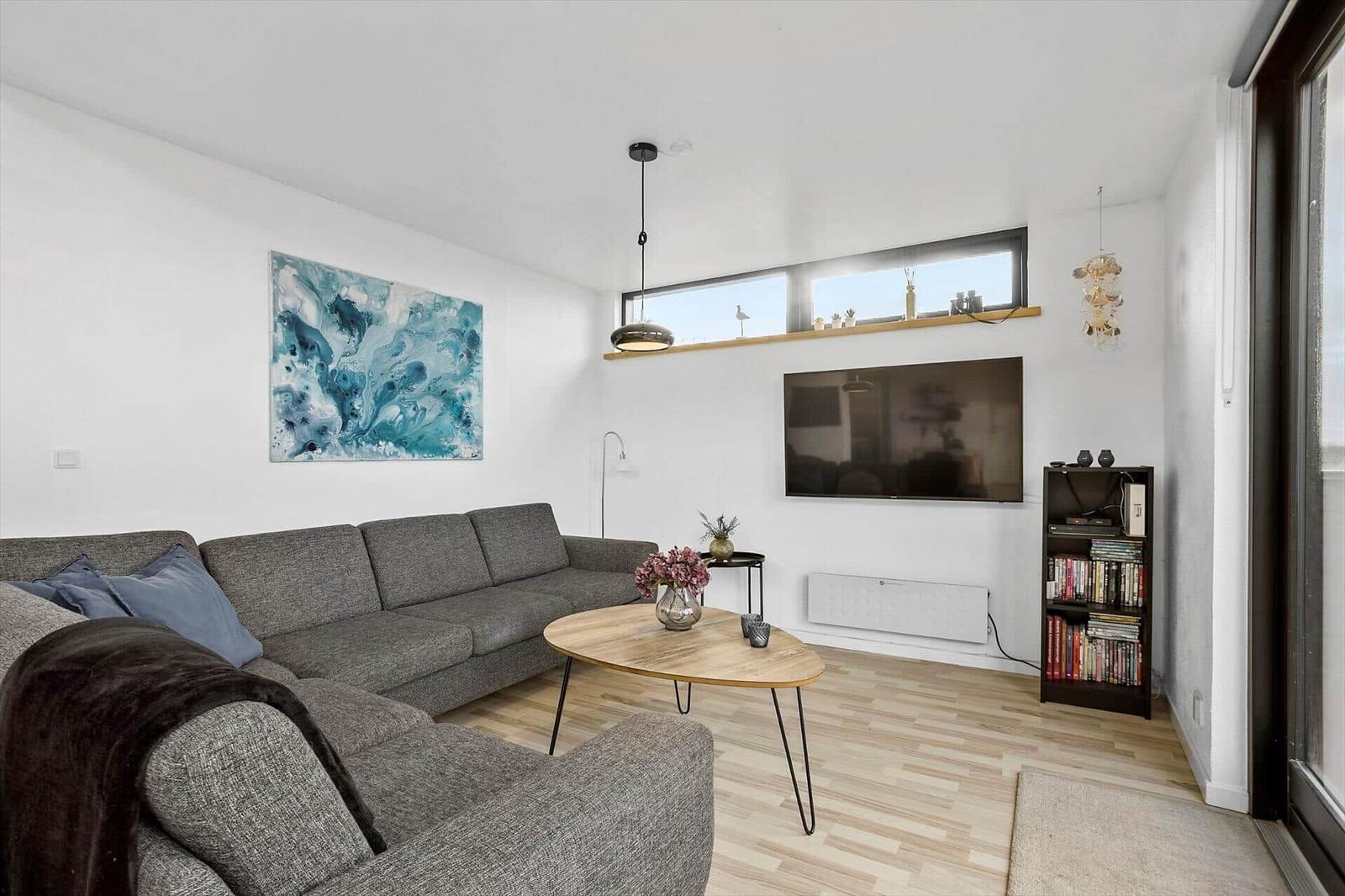 Living room with sofa, coffee table, and TV mounted on the wall.