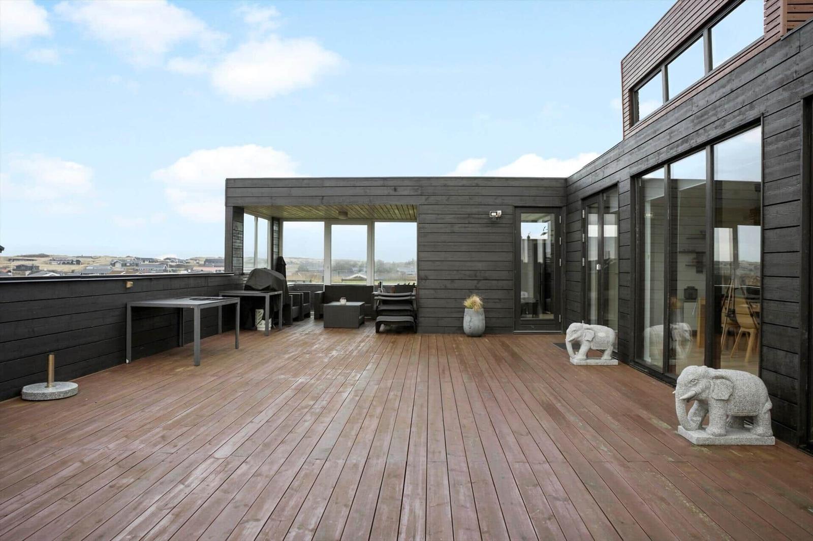 Large wooden terrace with seating and elephant statues. View of the landscape.