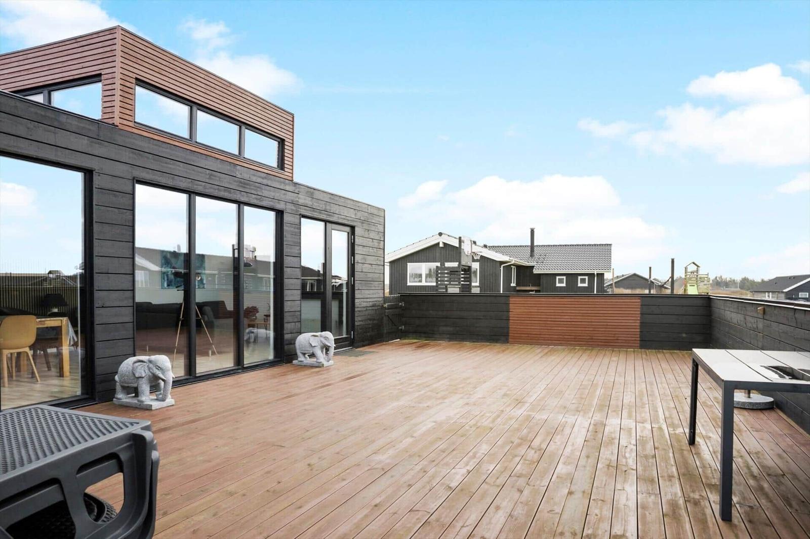 Deck with wooden floor, glass walls, and stone elephant statues. View of neighboring houses.