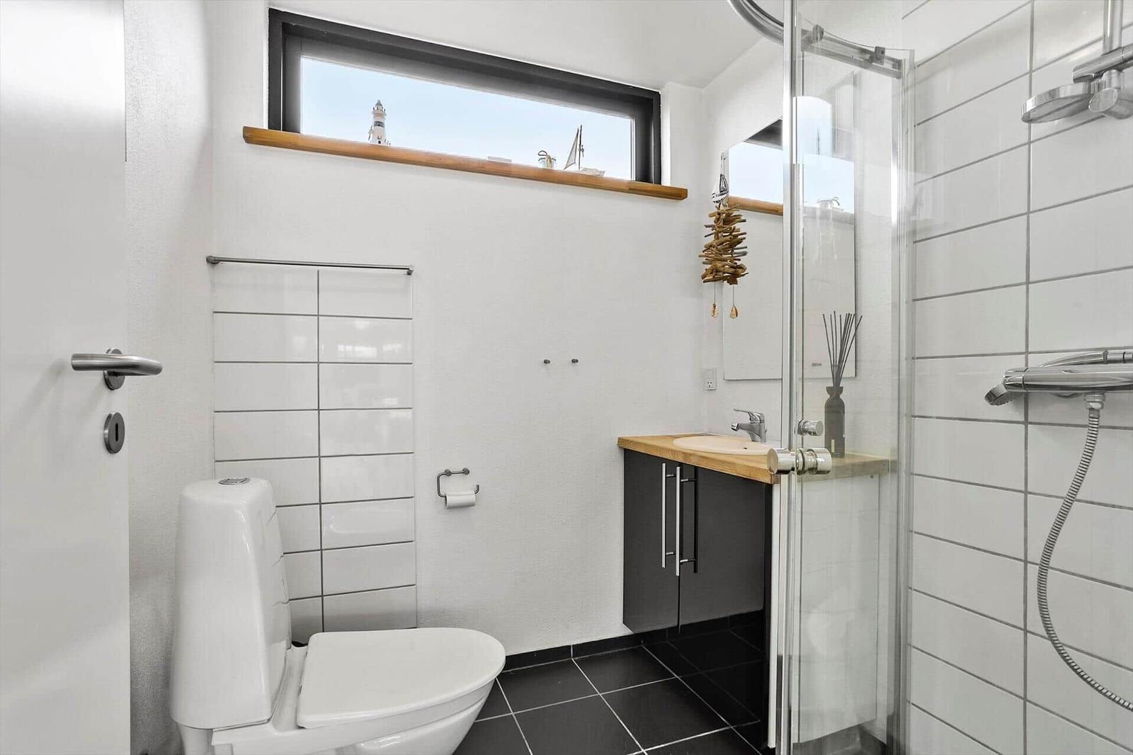 Bathroom with shower, sink and toilet. Window with view of lighthouse.